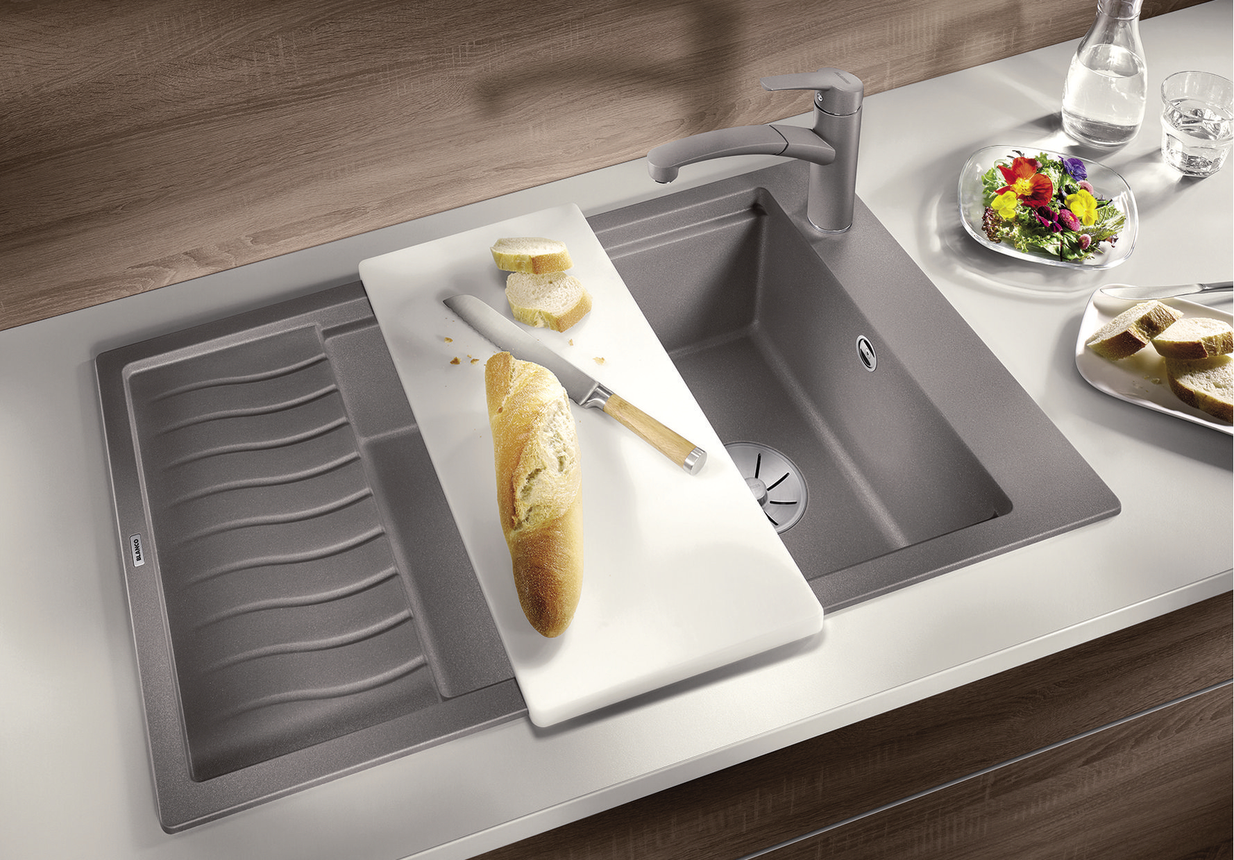 A baguette on a white plastic cutting board on a Silgranit sink